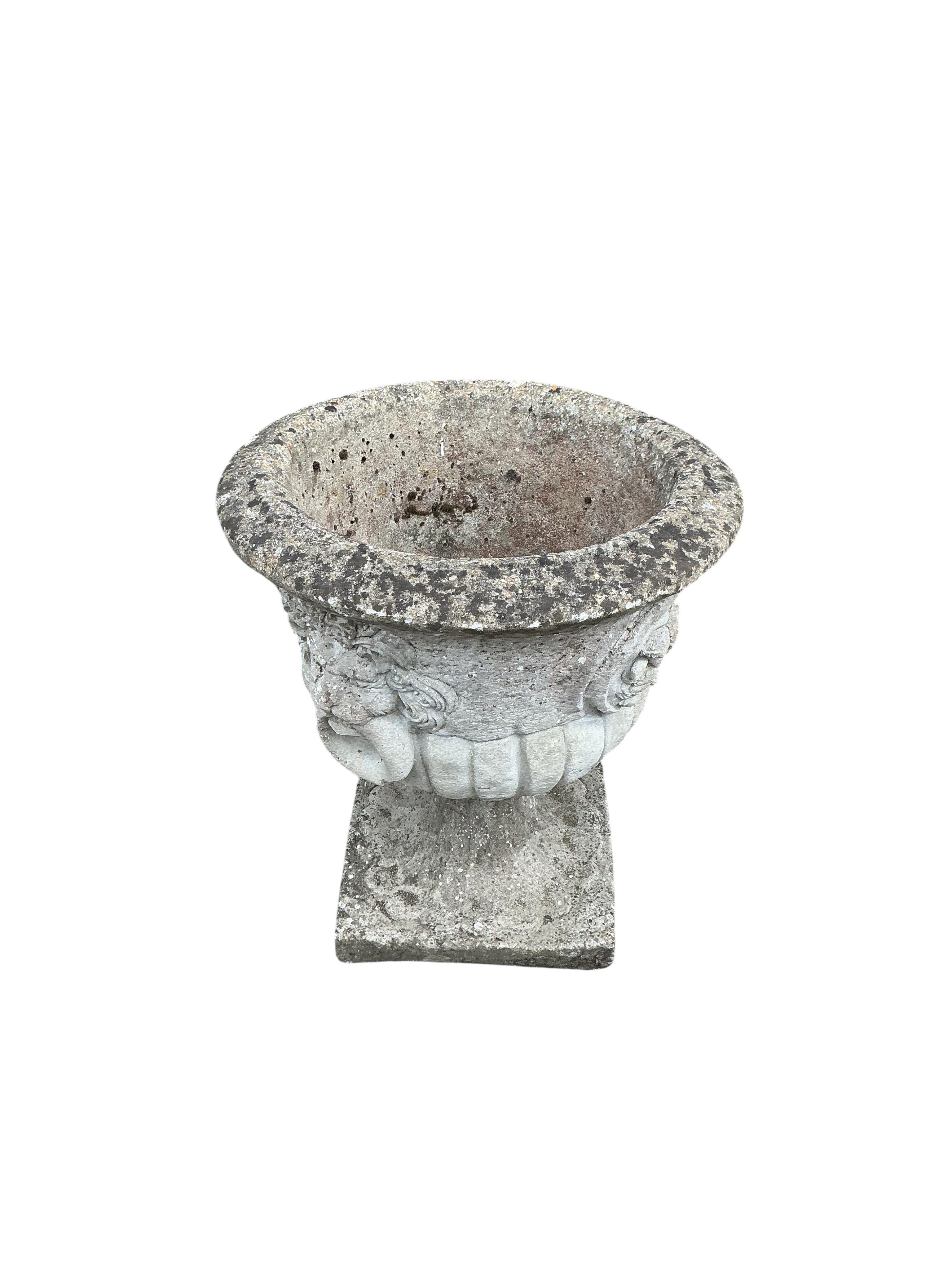 A pair of circular reconstituted stone garden urns with moulded lion mask ring decoration, diameter 53cm, height 60cm